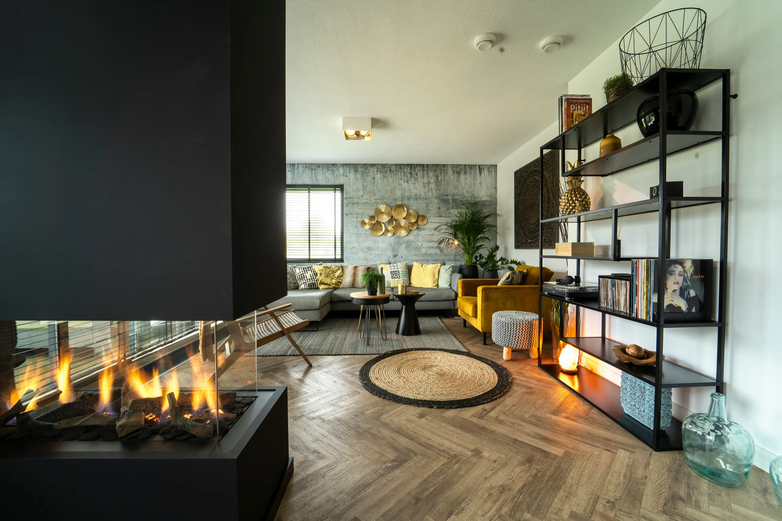 Nowoczesny salon z kominkiem, drewnianą podłogą i czarnym regałem